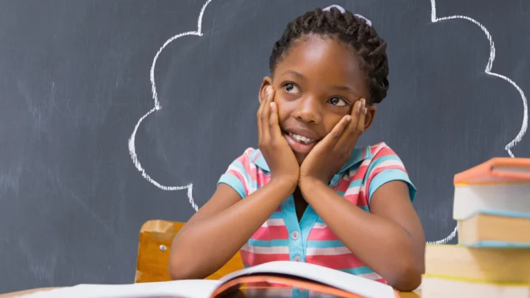 African schoolgirl daydreaming in class with open book and chalkboard in the background